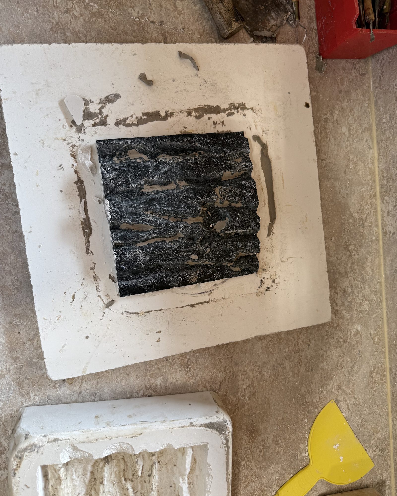 A dark bark-textured piece set in a plaster slab on the workbench.