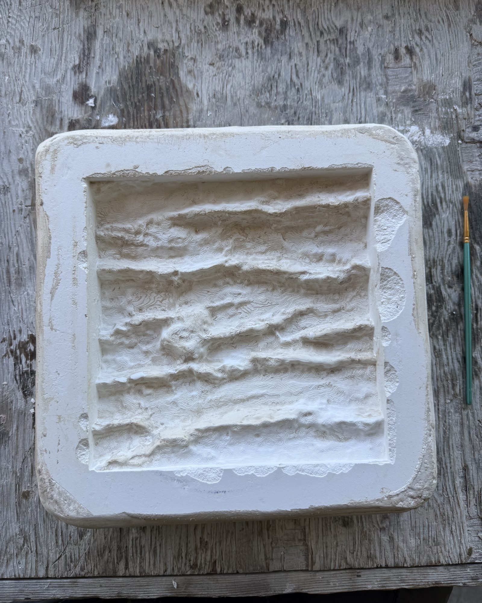 A white plaster mold carrying the ridged texture of cedar bark.